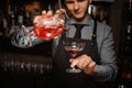 Young barman transfusing a fresh alcoholic cocktail into the cocktail glass Royalty Free Stock Photo