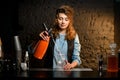 Young bartender girl pours carbonated drink to glass using siphons. Royalty Free Stock Photo