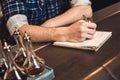 Young bartender leaning on bar counter writing inventory close-up