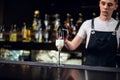 A young bartender pours champagne into a glass from a bottle on the bar Royalty Free Stock Photo