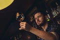 Young bartender standing at bar counter checking glass cleanliness Royalty Free Stock Photo