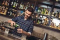 Young bartender standing at bar counter pouring alcohol into jigger joyful making cocktail Royalty Free Stock Photo