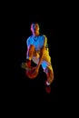 Young basketball athlete training dribbling technique in motion against black studio background in mixed neon light. Royalty Free Stock Photo