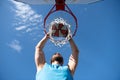 Young basketball player dunking basketball on outdoor court. Royalty Free Stock Photo