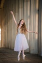 Young bayerina in a long white skirt stands in a graceful pose on pointes Royalty Free Stock Photo
