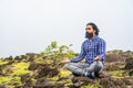 Young beard man with eyes closed doing meditation or yoga on top of hill - concept of self caring, health care and