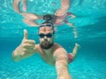 Young beard man with glasses diving in a blue clean water Royalty Free Stock Photo