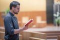 Young beard man wearing blue shirt praying with bible in modern church Royalty Free Stock Photo