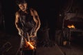 Young bearded blacksmith heats the metal