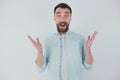 Young bearded brunette man wearing vasual t-shirt stands on isolated white background looking surprised , sideways posing Royalty Free Stock Photo