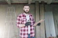 Young bearded businessman, builder, repairman, carpenter, architect, designer dressed in plaid shirt, goggles and gloves