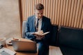 Young bearded businessman sitting in cafe and writing down notes during online webinar Royalty Free Stock Photo