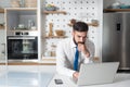 Young bearded businessman standing in the kitchen and check the company work list for his new business plan and  project on his la Royalty Free Stock Photo