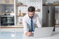 Young bearded businessman standing in the kitchen and check the company work list for his new business plan and  project on his la Royalty Free Stock Photo