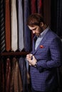 Young bearded businessman trying on custom tailored suit, buttoning jacket