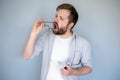 Young bearded Caucasian man cleans his glasses from dust and dirt, he breathes on the lenses and wipes them with shirt.