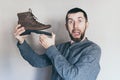 Man holding an old leather boot with torn sole, surprise and shock on his face