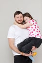 young bearded dad holds his little daughter in his hands. father hugging his child with love. man in white t-shirt and Royalty Free Stock Photo