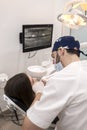 Young bearded male dentist drilling tooth to female patient Royalty Free Stock Photo