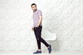 Young bearded fashion model in casual style is posing near white circle wall background. studio shot.