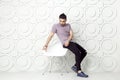 Young bearded fashion model in casual style is posing near white circle wall background. studio shot.