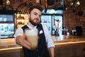 Young bearded good looking barista offering a cup of tasty cuppuchino