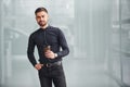 Young bearded guy in elegant clothes standing indoors against grey background Royalty Free Stock Photo