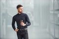 Young bearded guy in elegant clothes standing indoors against grey background Royalty Free Stock Photo