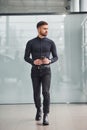 Young bearded guy in elegant clothes standing indoors against grey background Royalty Free Stock Photo