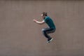 Young bearded guy sortsman jumping on the background of a pink street wall