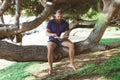 Young bearded handsome man reading the book sitting on tree trunk Royalty Free Stock Photo