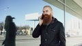 Young bearded hipster man concentrated talking on phone on citystreet and have conversation near office building Royalty Free Stock Photo