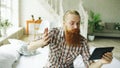 Young bearded man using tablet computer having video chat sitting in bed at home Royalty Free Stock Photo