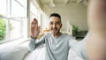 Young bearded man using tablet computer having video chat sitting in bed at home Royalty Free Stock Photo