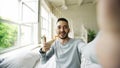 Young bearded man using tablet computer having video chat sitting in bed at home Royalty Free Stock Photo