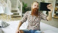 Young bearded man using tablet computer having video chat sitting in bed at home Royalty Free Stock Photo