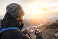 Young bearded hipster wearing a hat and sunglasses with Nordic walking sticks and a backpack moves in the mountains at