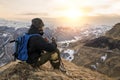 Young bearded hipster wearing a hat and sunglasses with Nordic walking sticks and a backpack moves in the mountains at