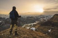 Young bearded hipster wearing a hat and sunglasses with Nordic walking sticks and a backpack moves in the mountains at