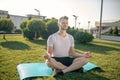 Young bearded male sitting in lotus pose outside, hands in Gyan mudra