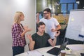 Young bearded man and blonde woamn argue with each other. They stand behind guy who meditates. He keep eyes closed and Royalty Free Stock Photo