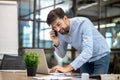 Young bearded man in a blue shirt talking on the phone and checking his mail Royalty Free Stock Photo