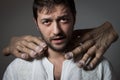 Young bearded man choked by two huge hands