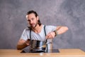 Young bearded man with cooking pot and egg whish