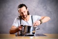 Young bearded man with cooking pot and egg whish