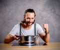 Young bearded man with cooking pot and egg whish