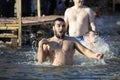 Young bearded man crossing himself plunging into icy water during the feast Epiphany on the Dnieper River