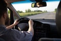 Young bearded man driving a car on old highway. Both hands holding a steering wheel Royalty Free Stock Photo