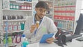 A young bearded man examines medicine while using a tablet in an indoor pharmacy setting Royalty Free Stock Photo