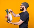 A young bearded man is holding a pouch with some groceries in it and smiling is giving them away Royalty Free Stock Photo